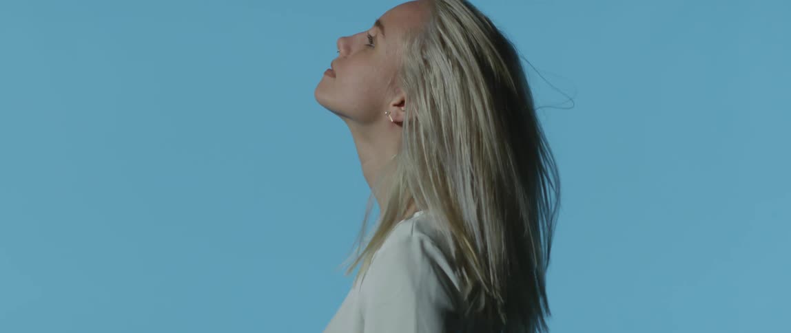 A teenager flips her hair back in front of a back drop for a photo shoot
