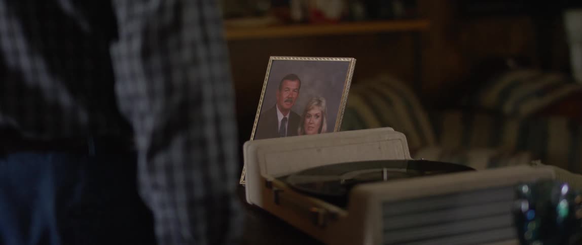 A man adjusts a picture frame placed next to a record player at his home