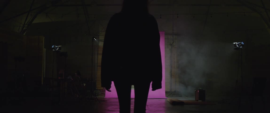 Woman walks forward away from a pink light