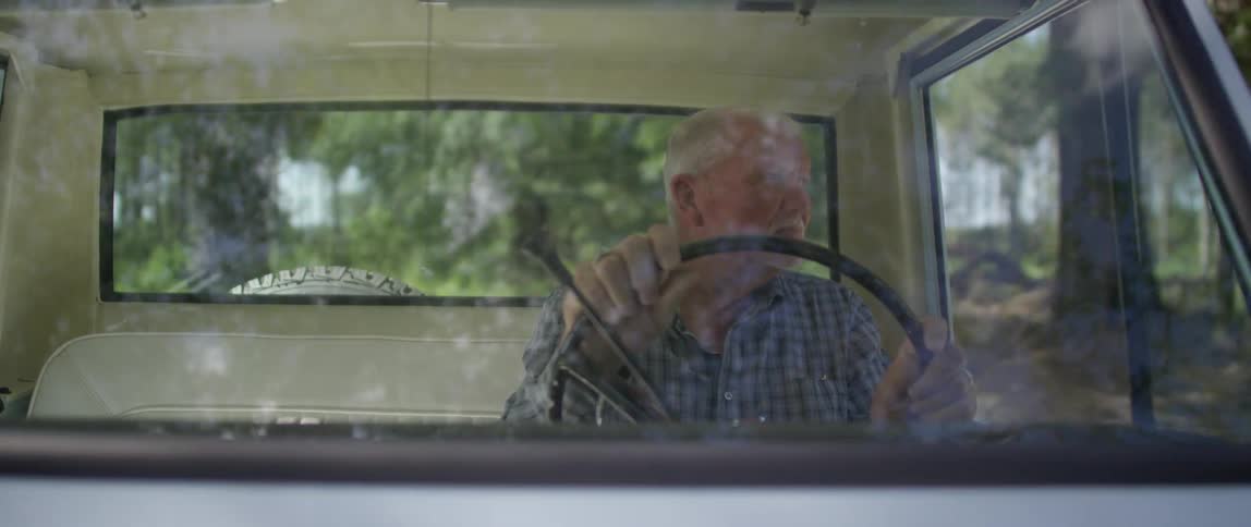 Elderly man driving in classic car on road in the countryside
