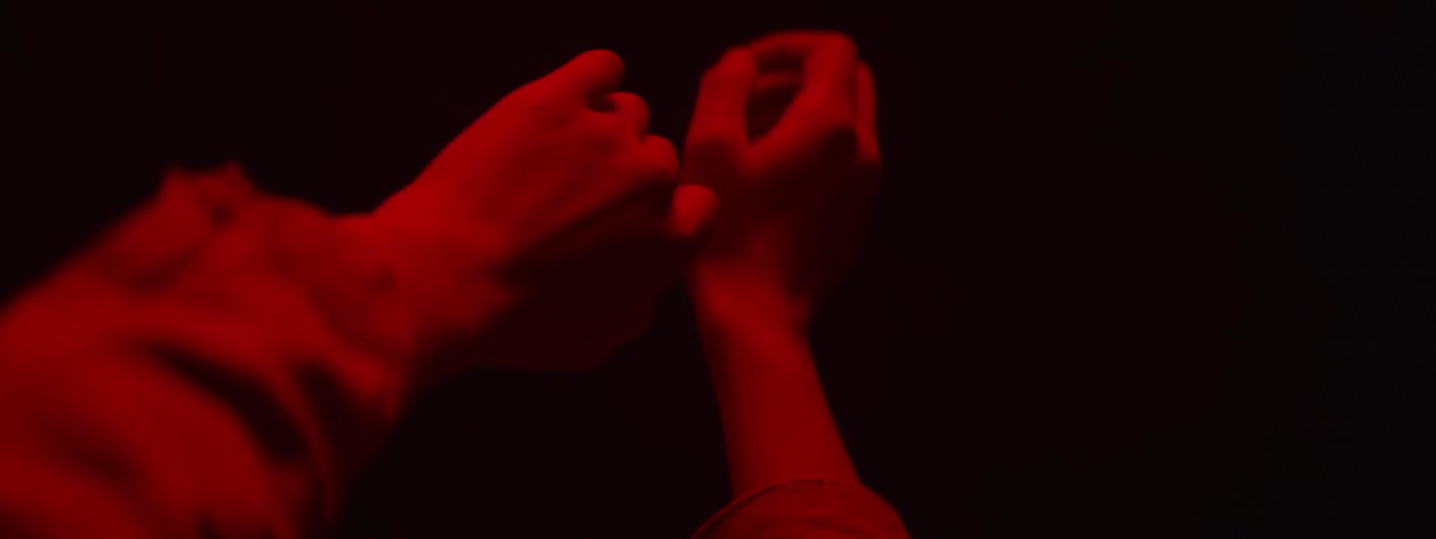 Two hands touch lit up by garish red light
