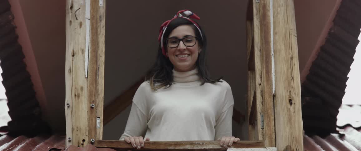 Woman opens the windows and smilingly stares at the camera