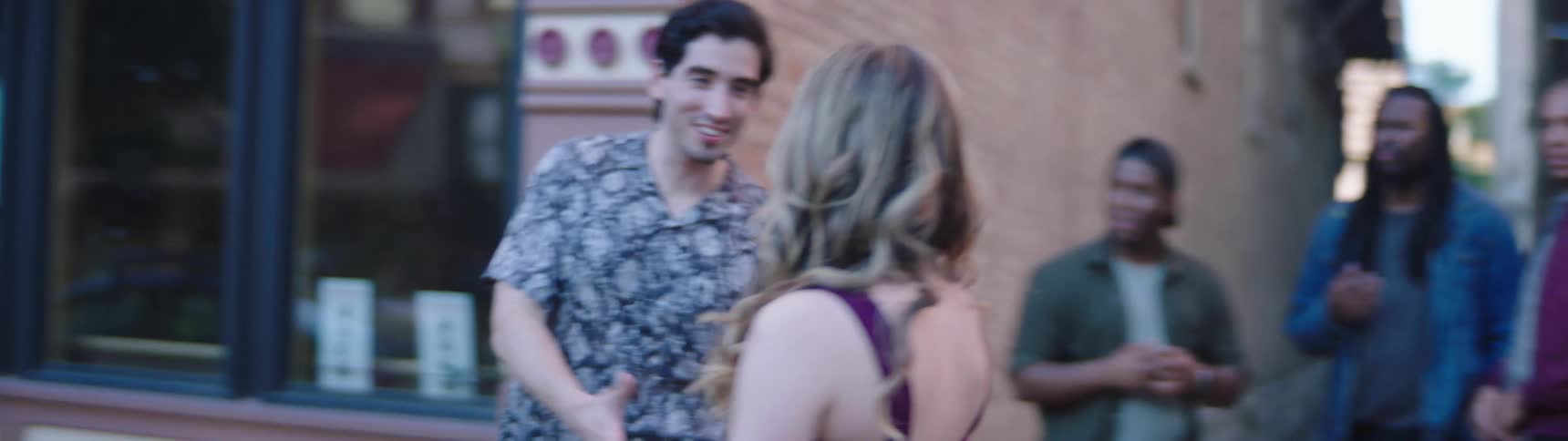 A young man with his friends approaches a woman on the street who pushes him away