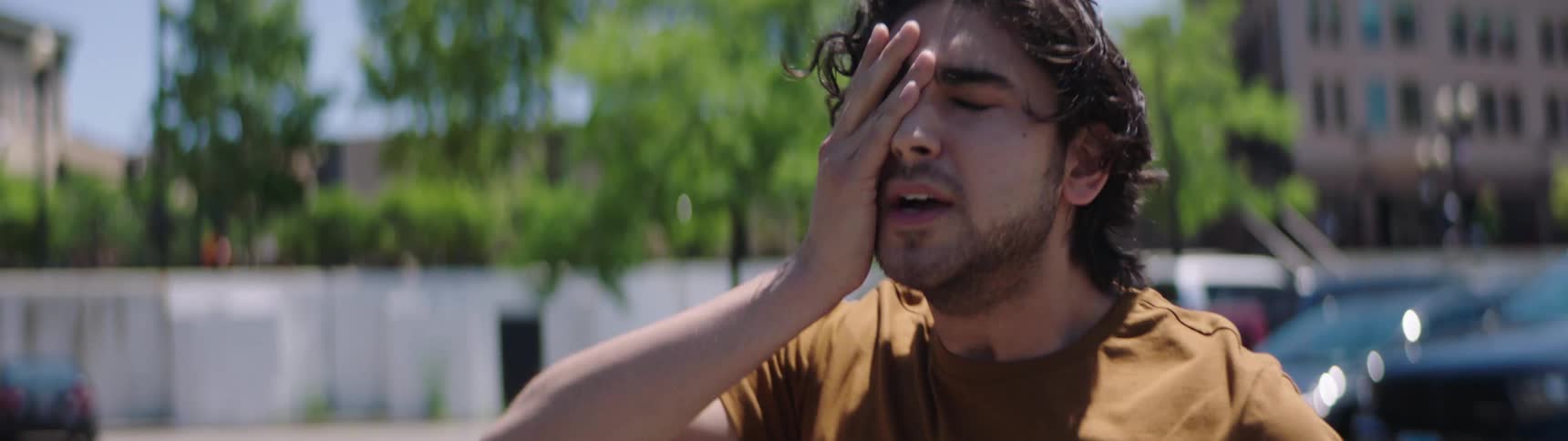 A man stands in a parking lot and looks around with a very panicked look on his face