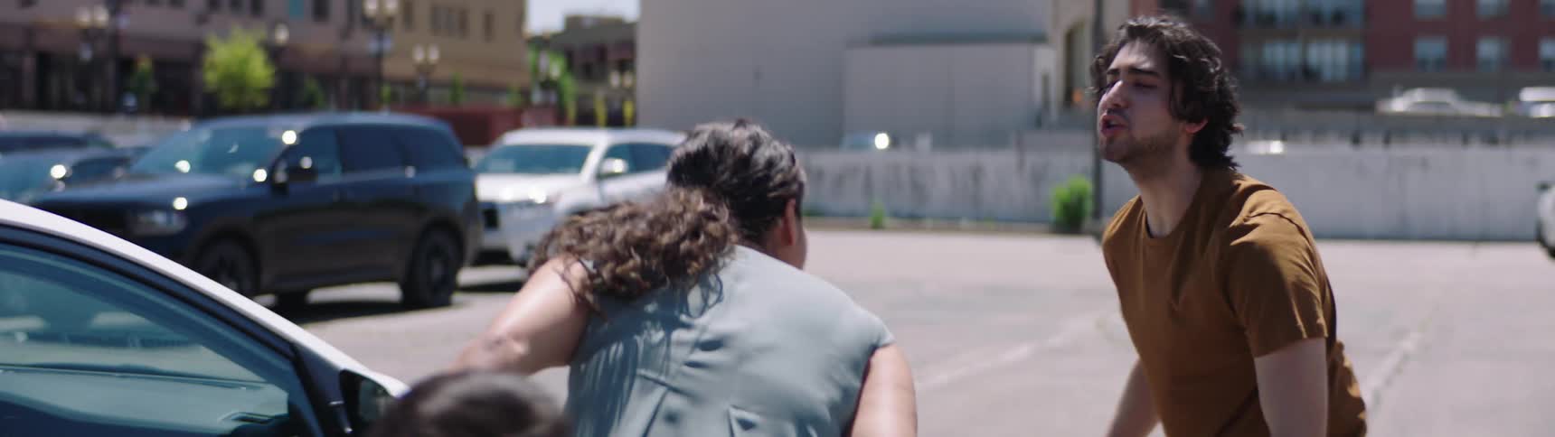 A woman walks towards her car with her son as a man chases after her and grabs her arm