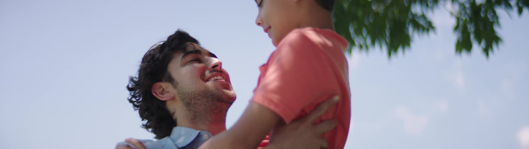 Father holds his son affectionately in the public park