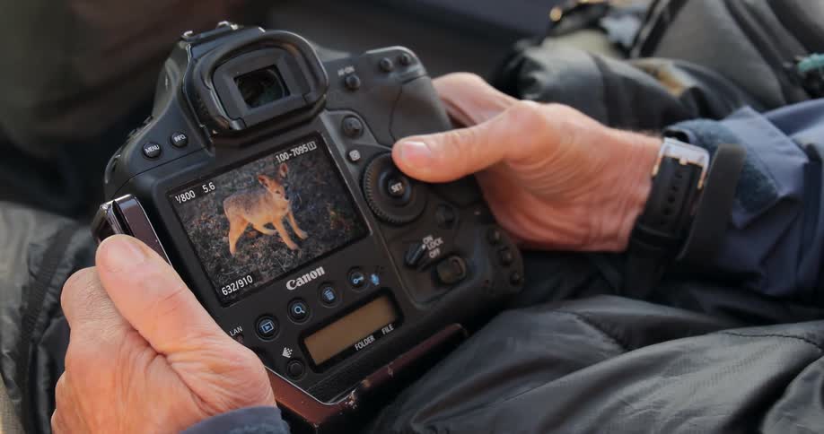 A man sits and looks through videos on a camera