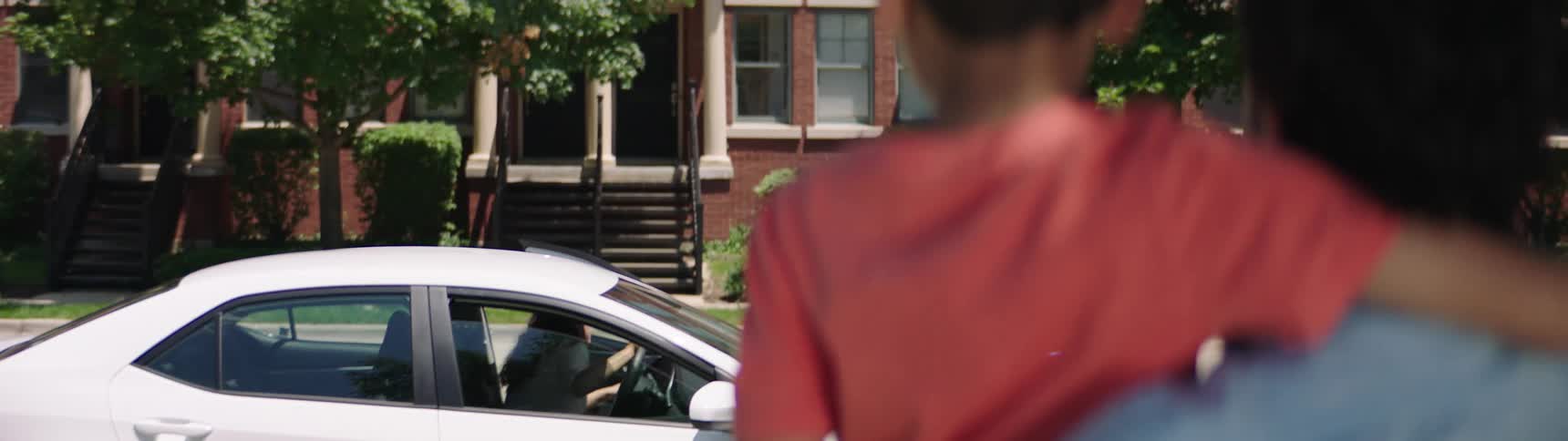 A woman gets out of her car and looks at her husband and son