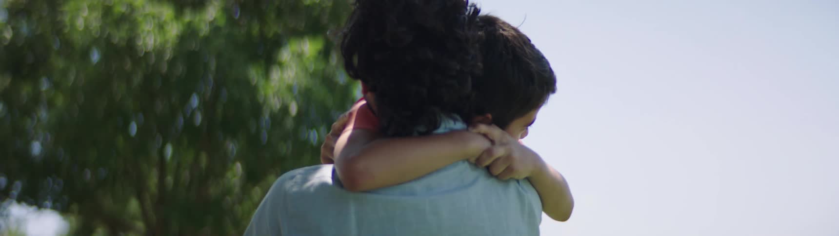 Father and son cuddle affectionately in the public park
