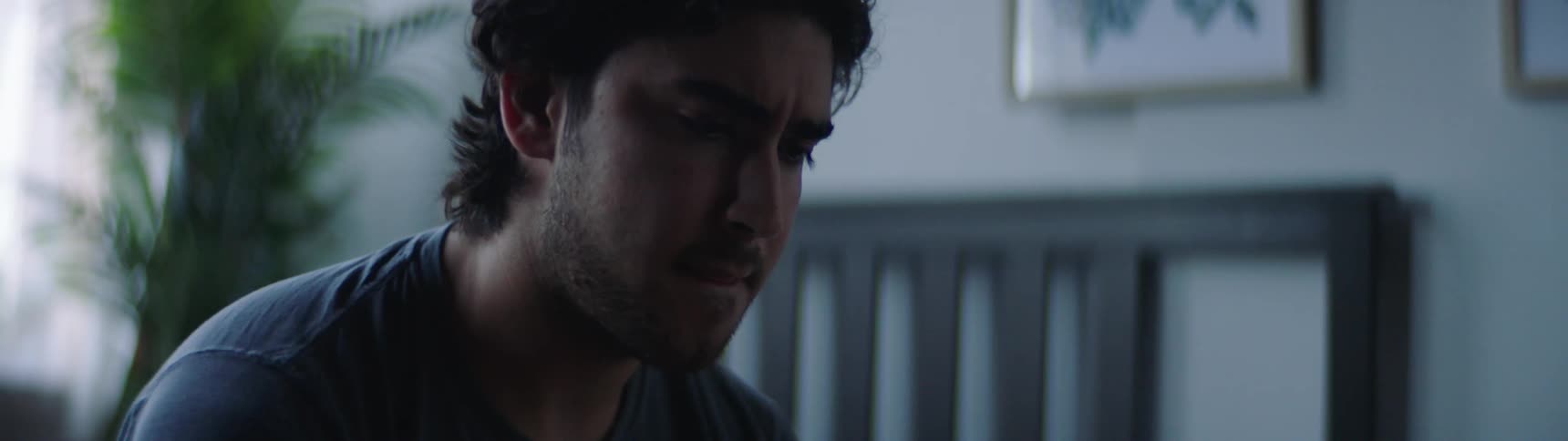 A man sits on his bed and looks at his cell phone