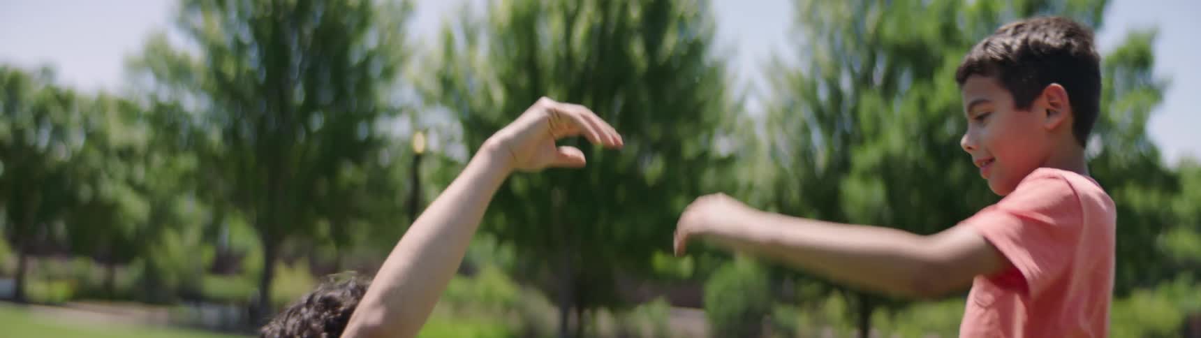 Father and son high five in the park then sit on grass