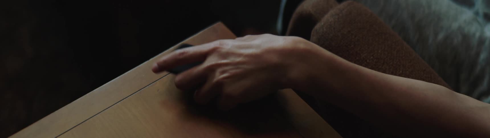 Man sitting on a sofa watches television and uses a smartphone in the living room