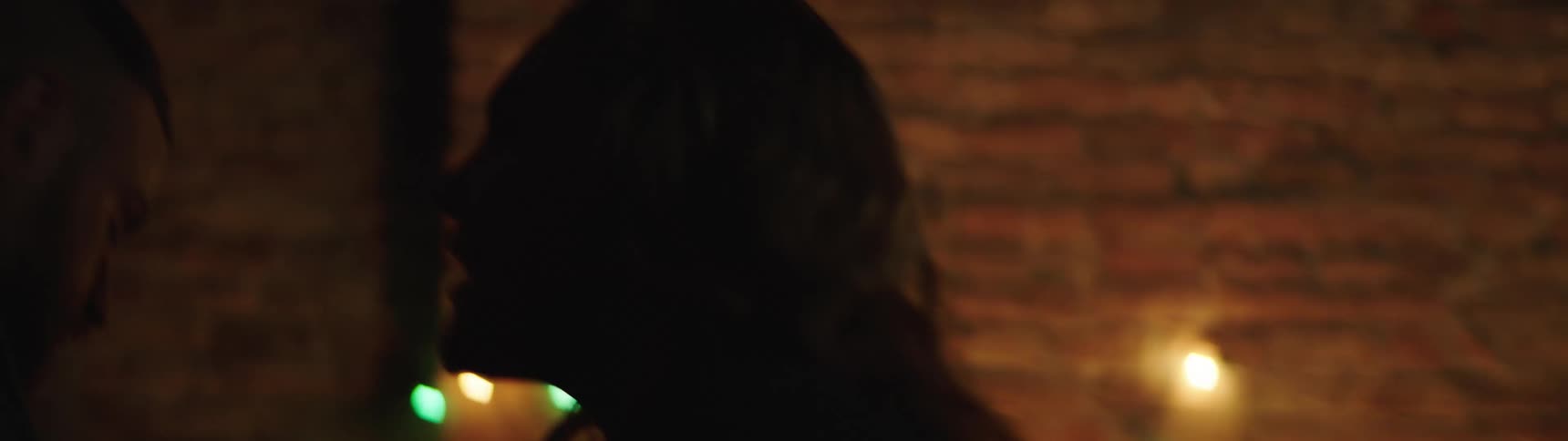 Man and woman dance in a room decorated with colored lights