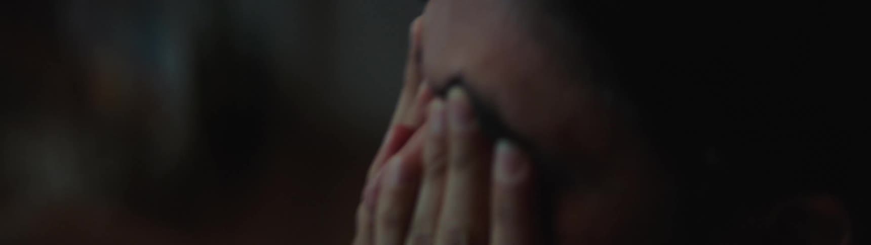 Man rubs eyes and temples in dim light