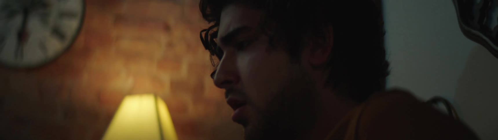 A man cowards in the corner of a room with a look of fear