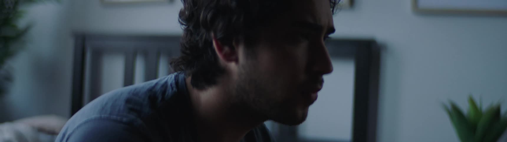A man sits on his bed looking depressed and then stands up