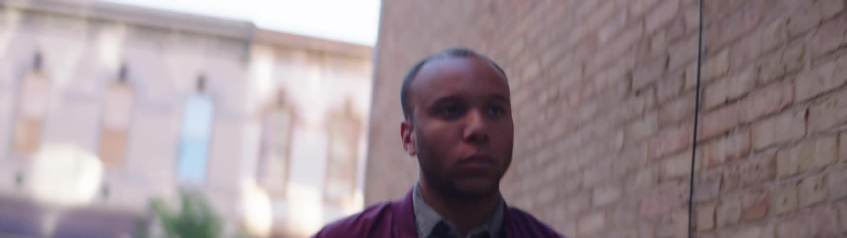 A man walking down the street puts his face in his hands