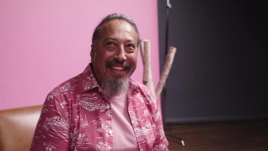 Older man with beard looks at camera and smiles and laughs