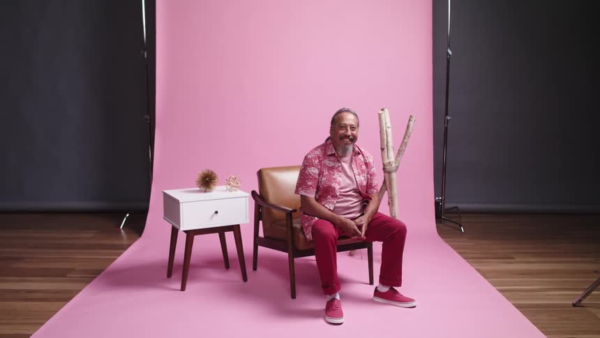 A man sits on some kind of set and laughs