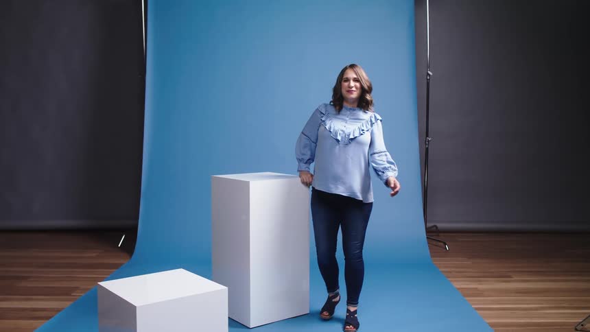 Woman walking toward white box and posing for a photo shoot