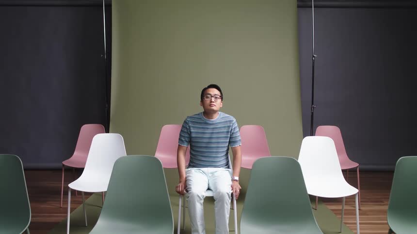 Man walking into photo shoot then sitting on white chair