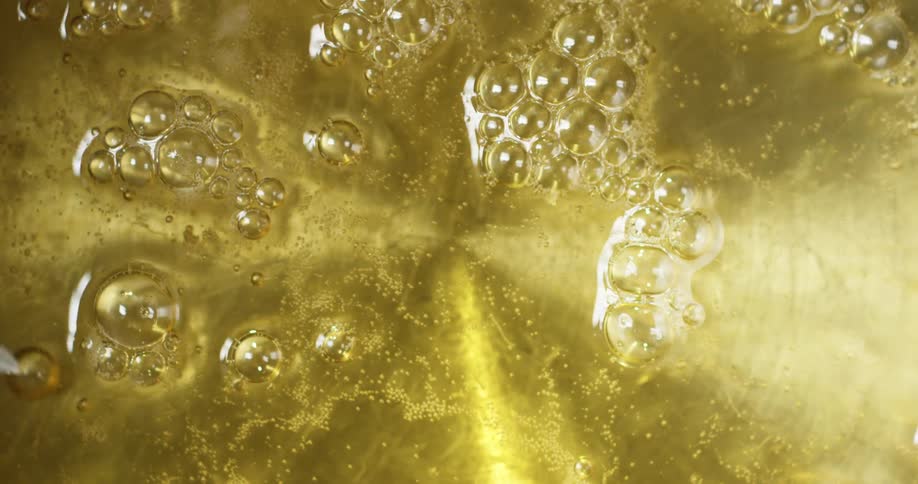 Bubbles form on the surface of oil heating in a pan