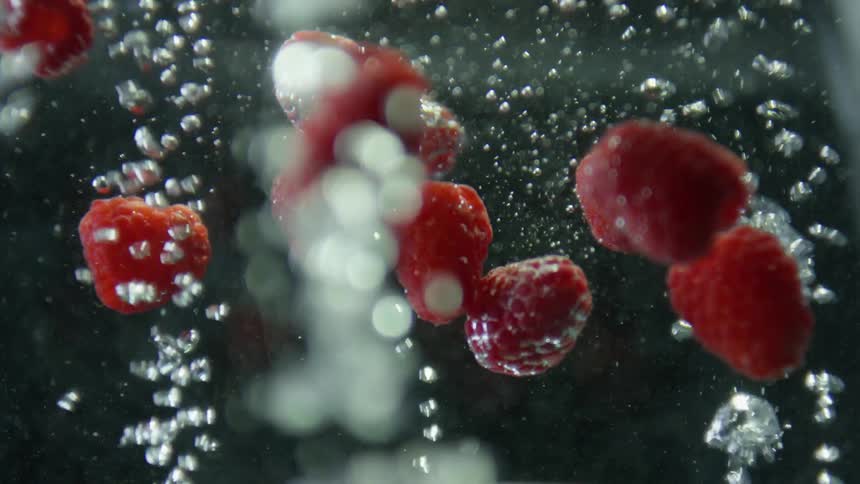 Raspberries falling into boiling water with bubbles