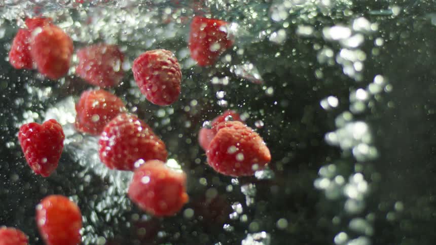 Raspberries are being dropped into water