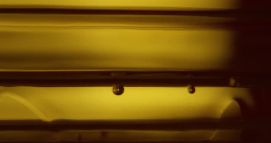 Small balls float in clear liquid against glowing and shadowy background