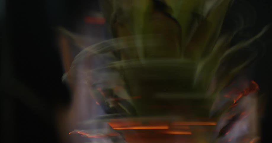 A vase shaped object spins rapidly while on fire