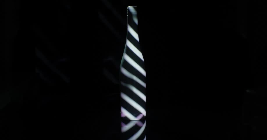 Bars of light projected on a dark wine bottle
