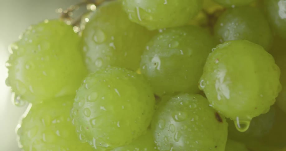 A bundle of green grapes covered in moisture spin around