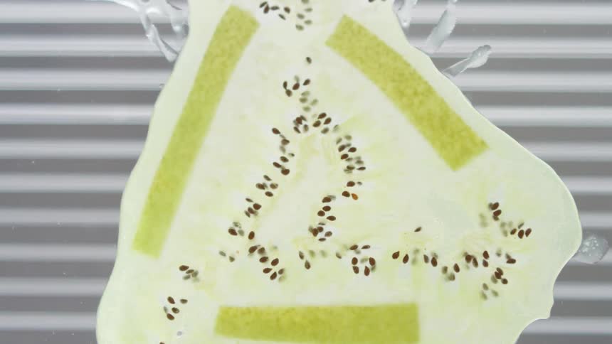 A piece of kiwi fruit drops and splatters