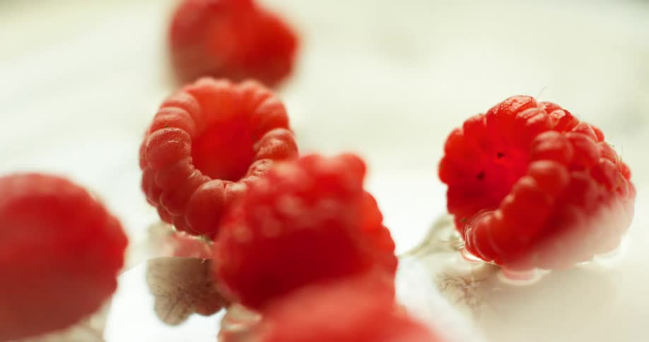 Red raspberries surrounded by smoke spin around on a plate