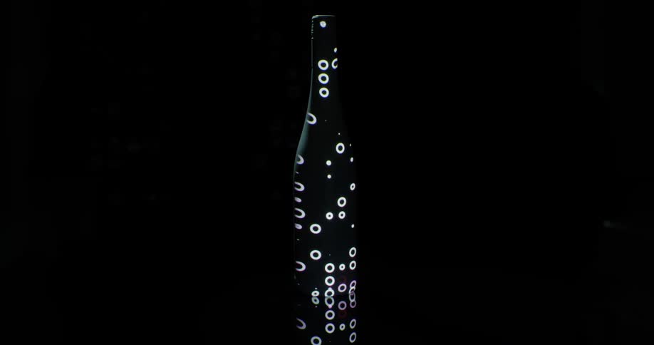 White circles and spots appear on black bottle against black background