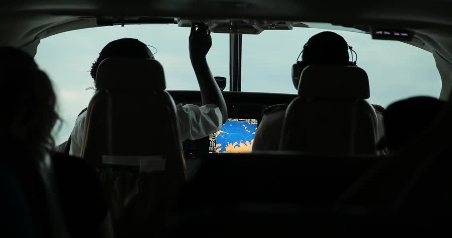 A pilot adjusts knobs during flight