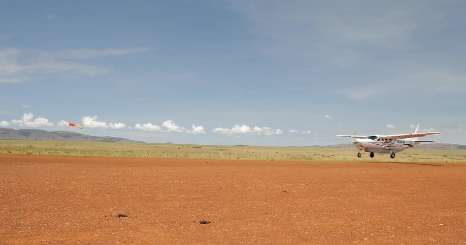 A plane takes off from a dirt runway