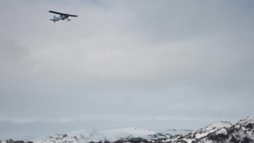 The plane flies over the frozen lake