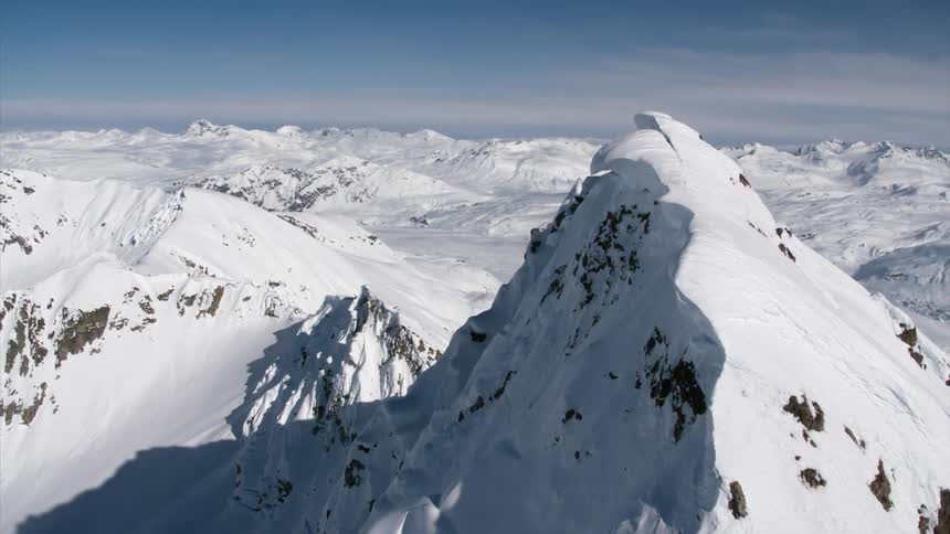 A snow covered mountain peak hides an expansive mountain range stretching to the horizon