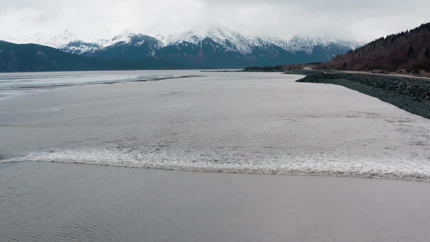 A lake near a road with mountains in the background