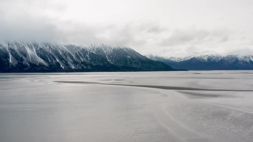 Freezing waters in front of snow covered mountains on an overcast day
