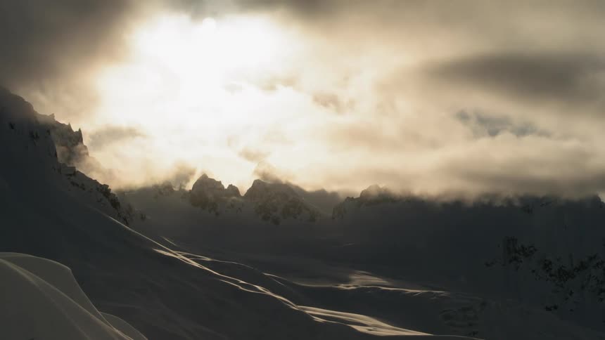 A cloudy sky hangs over a snow covered mountain range