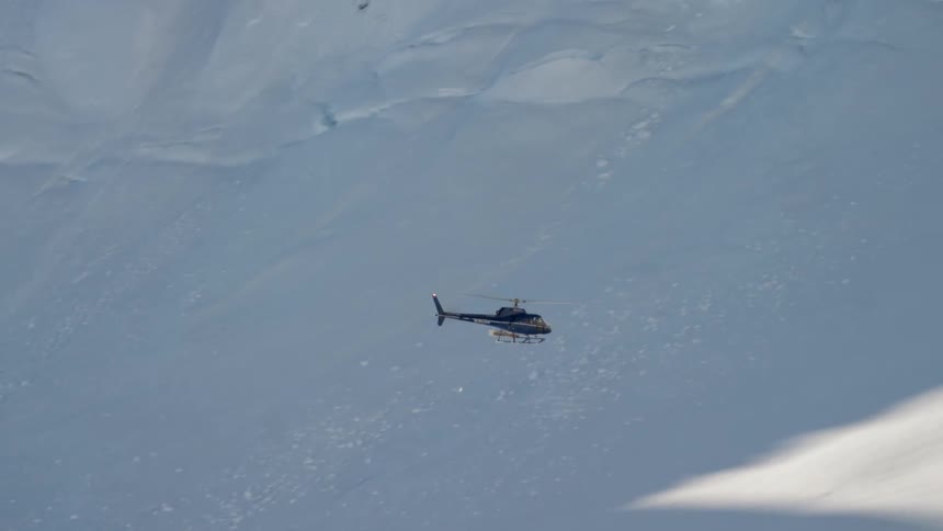 An aerial view of a helicopter flying over an arctic area is displayed
