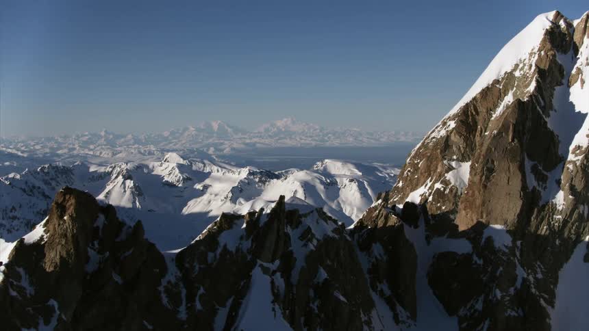 Sun highlights parts of snow covered mountain range while casting other parts into shadow