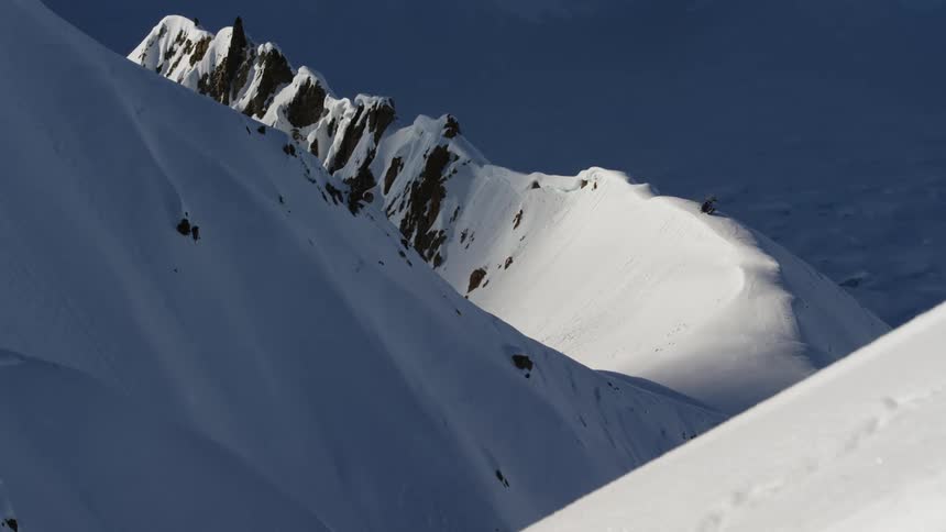 Snow covered rugged mountain peaks in daylight and shadow