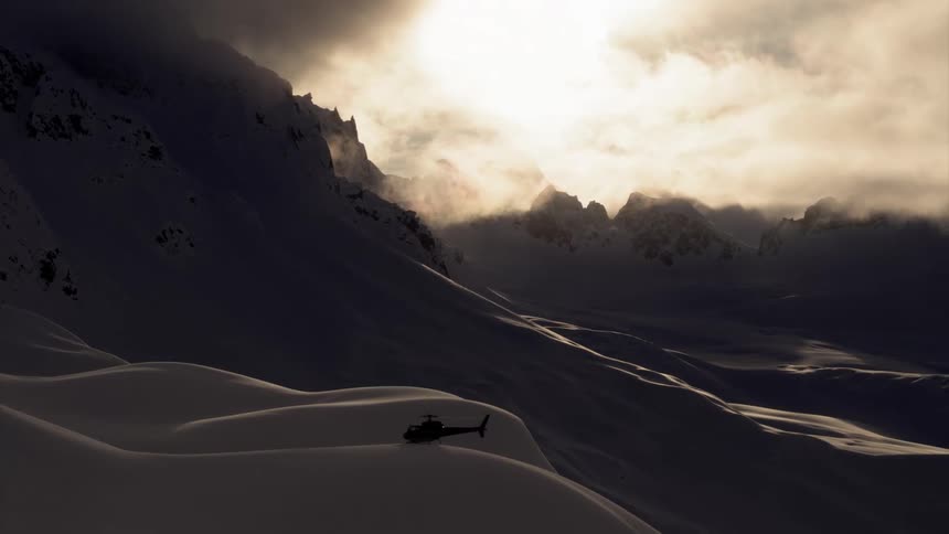 A helicopter sits on a snow covered mountain ridge