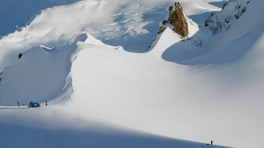 Helicopter landed on the snow covered slopes of a mountain range