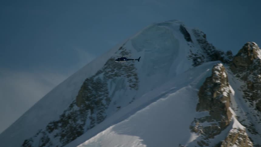 A helicopter is flying towards the mountain