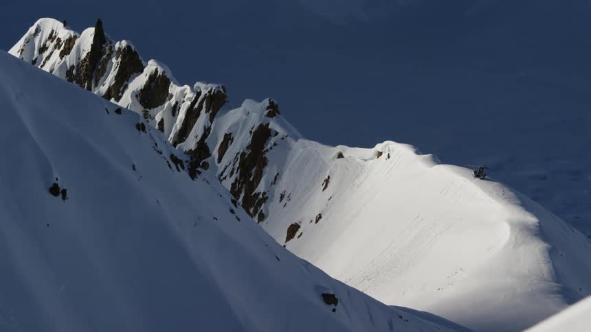 Helicopter has landed on the snow covered peaks of a mountain range