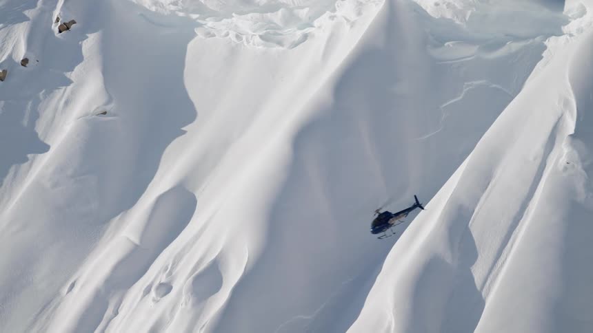A helicopter flies in a circle around a giant snow covered mountain